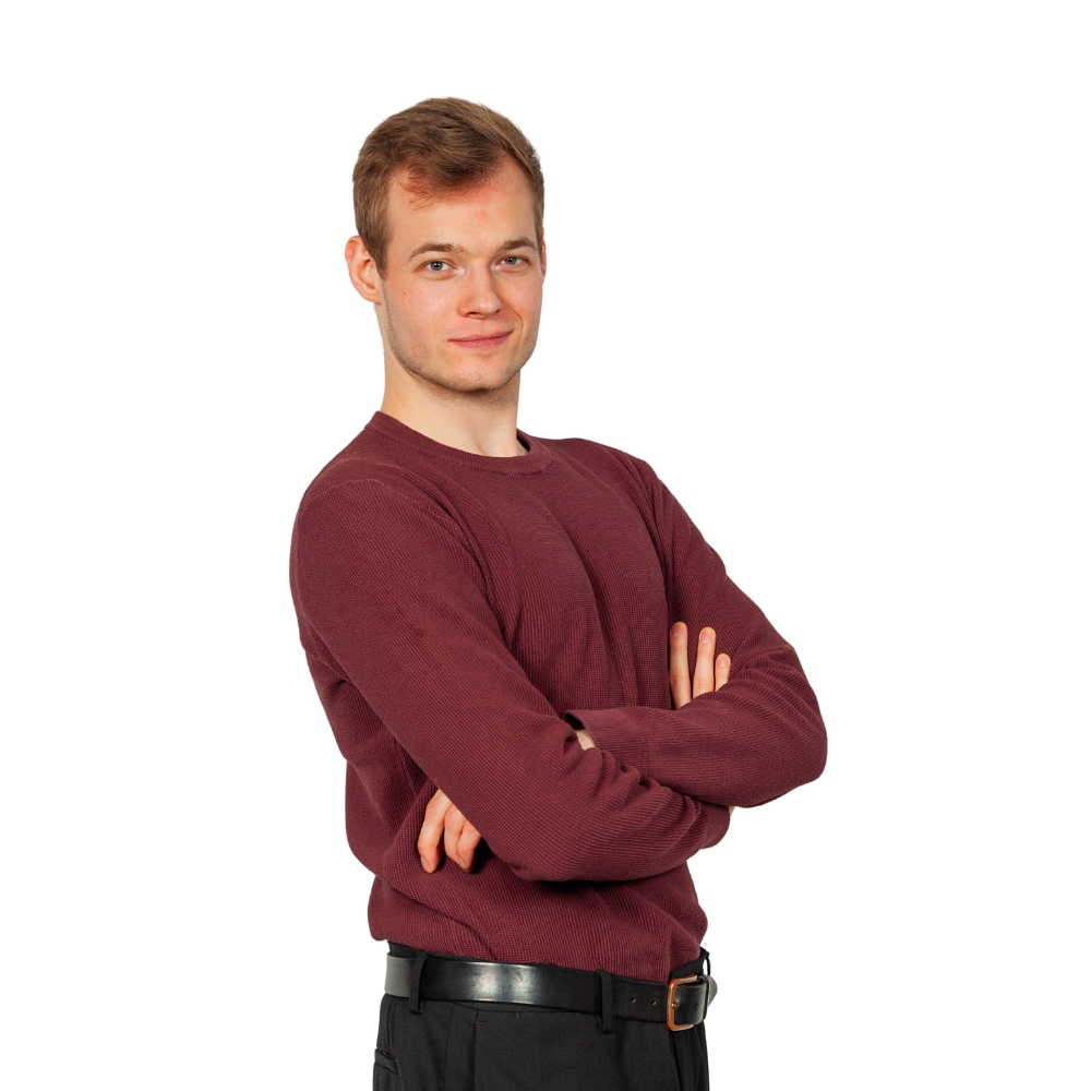 A candid photograph capturing Frederik O. Petersen, a renowned author and chef, standing confidently with a warm smile, arms crossed, and dressed in a comfortable yet stylish ensemble consisting of a vibrant red sweater, neatly tailored black pants, and a sleek black belt. With his welcoming demeanor and professional attire, Frederik embodies the essence of culinary expertise and passion for cooking, offering a glimpse into the world of gastronomy and the inspiration behind his acclaimed cookbook, YouTheChef - Global Kitchen. This image showcases the personable nature of the author, inviting readers to explore the diverse array of recipes and culinary adventures presented within the pages of his celebrated book.